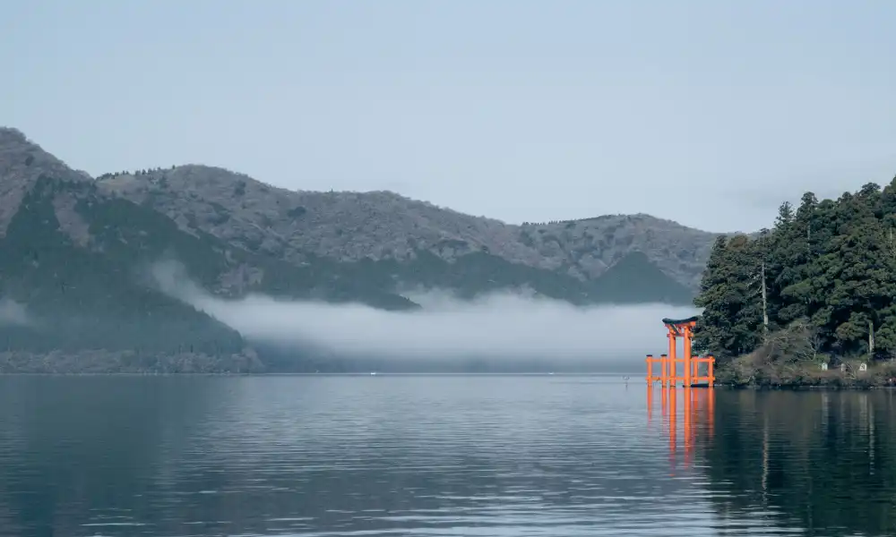 Two weeks in Japan travel guide featuring peaceful lake view with red torii gate and mountain mist