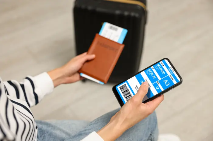 Air passenger rights UK &ndash; traveller reviewing UK261 flight delay compensation claim on mobile phone at airport